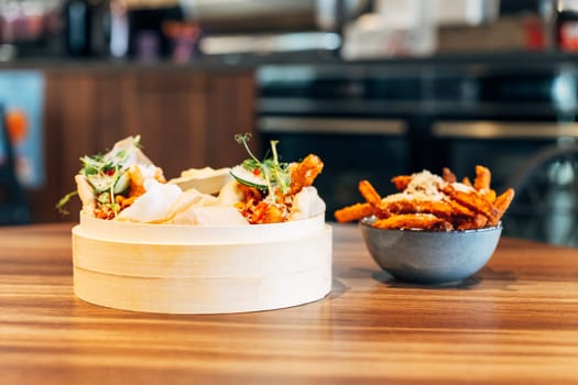 Bamboo Steamer with Soft Bao Buns and Sweet Potato Fries in a Restaurant Setting.