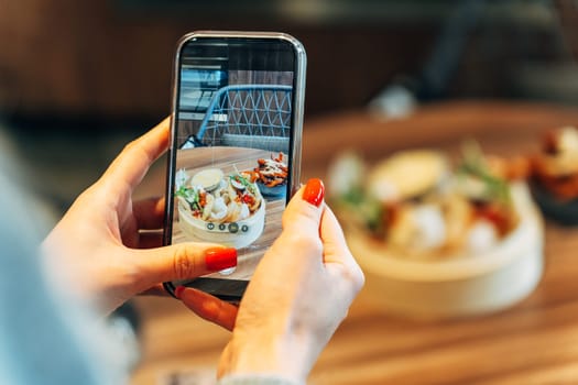 Woman taking a photo of Asian street food with smartphone in a modern restaurant.