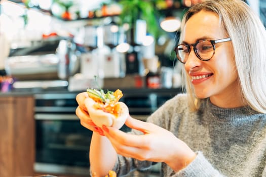 Smiling Woman Holding a Bao Bun with Fresh Ingredients in a Modern Cafe.