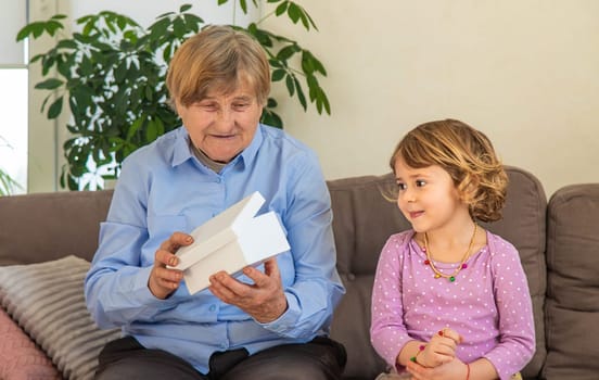 Granddaughter gives her grandmother a gift. Selective focus. Kid.