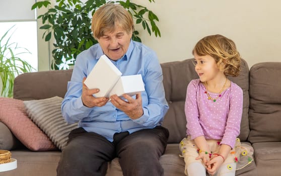Granddaughter gives her grandmother a gift. Selective focus. Kid.