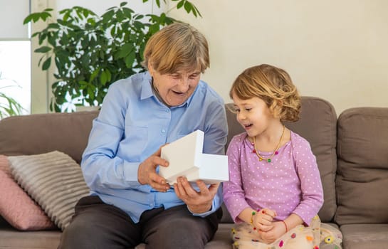 Granddaughter gives her grandmother a gift. Selective focus. Kid.