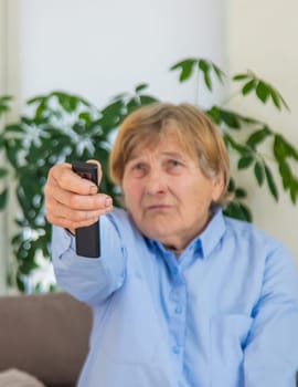 Old woman with remote control in her hands. Selective focus. people,
