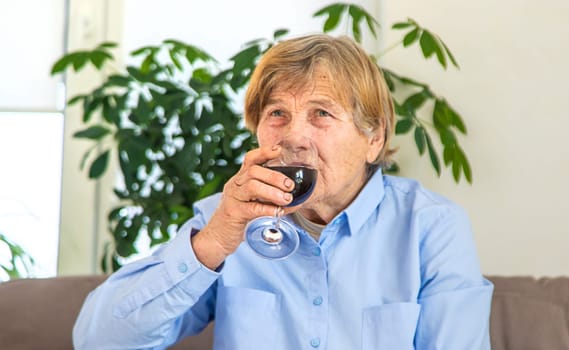 Old woman drinking wine. Selective focus. People,