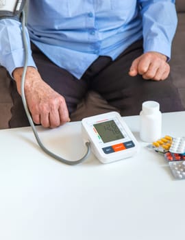 An old woman measures her blood pressure. Selective focus. people,