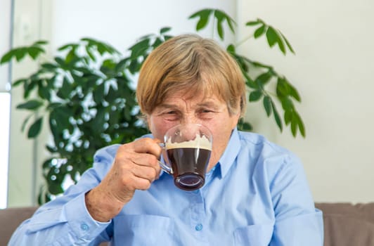 Old woman drinking coffee. Selective focus. People,