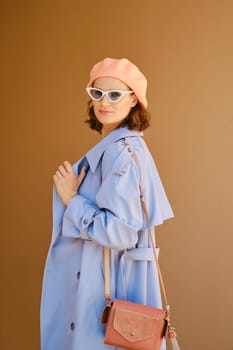 Pretty woman in blue coat, hat and sunglasses turned back