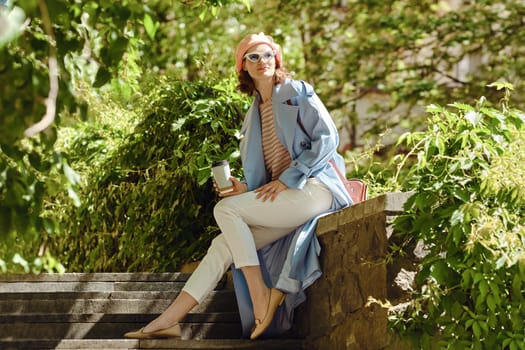 A happy woman sitting among plants, smiling in casual fashionable clothing