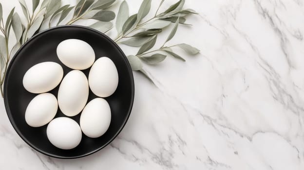 A minimalist Easter centerpiece showcases white eggs arranged on a black plate surrounded by eucalyptus leaves atop a sleek marble countertop.