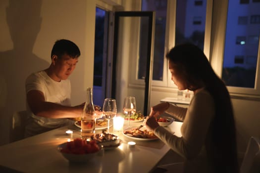 Young couple having a romantic candlelit dinner at their cozy home