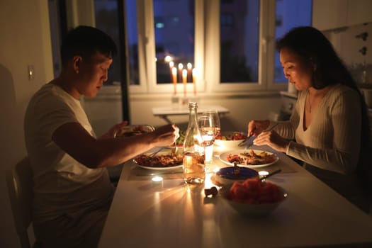 Young asian couple eating dinner by candlelight at their home