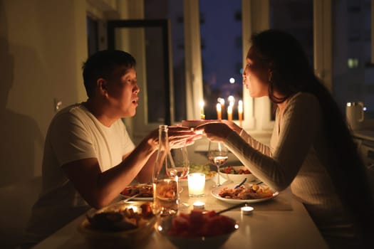 Romantic couple celebrating birthday with a cake and candles during a cozy dinner at home