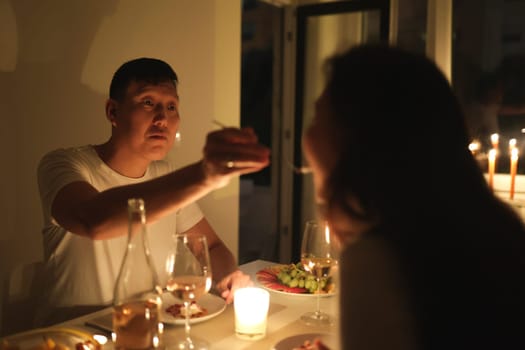 Couple enjoying romantic evening with wine, cheese, and fruit by candlelight