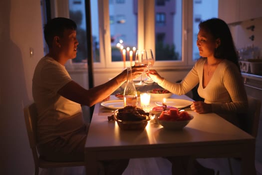 Asian couple enjoying romantic evening with wine and candlelight dinner at home