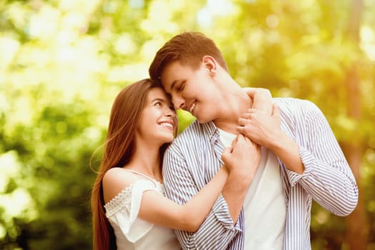Portrait of beautiful affectionate couple hugging at park on sunny summer day