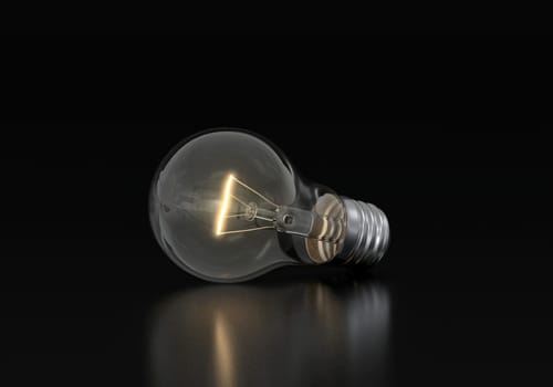 An incandescent light bulb is burning on a black background
