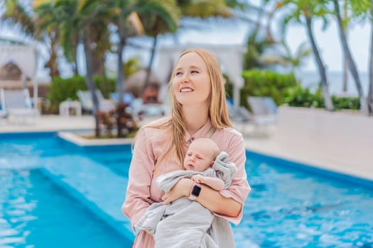A mother holds her baby near a tropical pool, surrounded by lush greenery. This heartwarming moment captures family bonding, maternal love, and the serene beauty of a tropical getaway, perfect for relaxation and connection.
