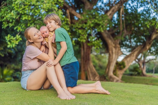 Young mother, teenage son, and one-month-old baby enjoying quality family time in the park. Multigenerational bonding and outdoor family love concept.
