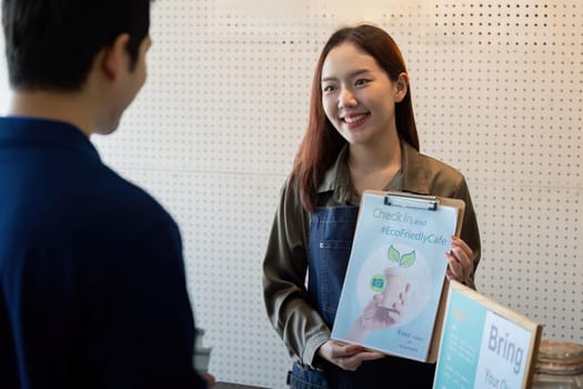 A barista holds a sign promoting check-ins and sustainable practices in a cafe dedicated to eco-friendly solutions.