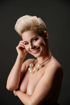 A confident woman poses topless with striking accessories, exuding beauty and elegance against a dark backdrop.
