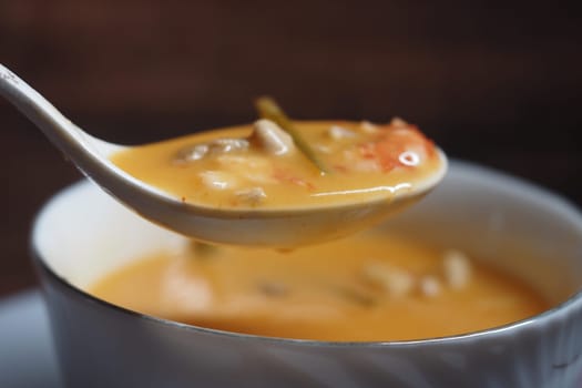 A spoonful of flavorful creamy soup filled with vegetables and herbs.