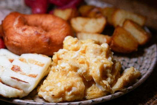 A delicious breakfast with scrambled eggs, cheese, and golden potatoes.
