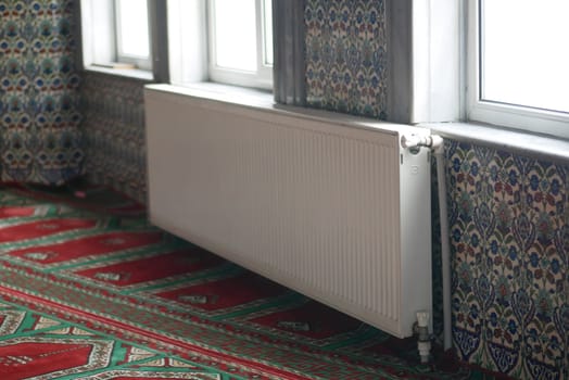 A radiator sits against vibrant patterned wallpaper and carpet.