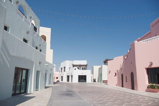 Brightly colored buildings line the pathway in a sunlit town.