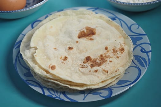 Freshly cooked flatbreads stacked on a decorative plate ready to serve.
