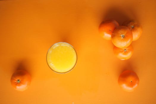 Bright orange background features a glass of fresh juice and several oranges.