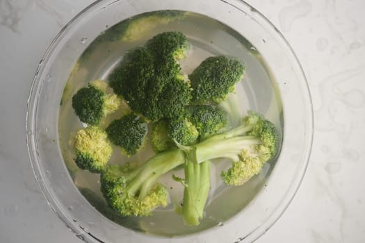 Fresh broccoli is soaking in water to clean and prepare for cooking.