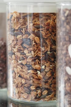 A jar filled with granola is displayed on a kitchen shelf.