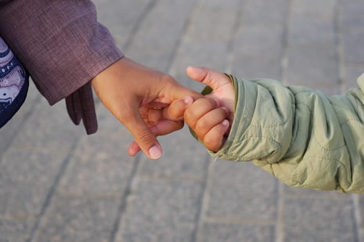 An adult and a child hold hands while walking along a plaza.