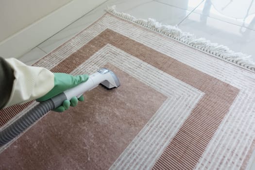A person utilizes a cleaning tool on a dusty carpet to refresh its look.