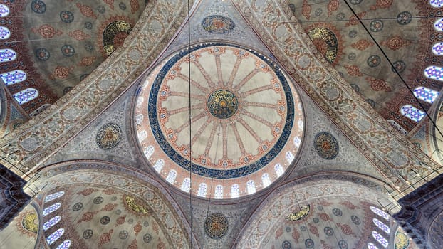 Visitors admire ornate ceiling details inside an ancient mosque.