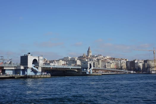 Galata Bridge spans the water, with city buildings and a tower in background.