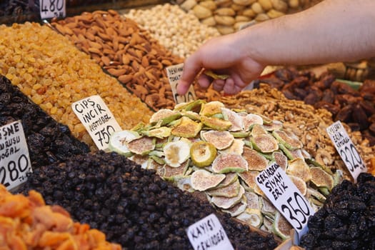 A customer selects dried fruits from a vibrant market display.