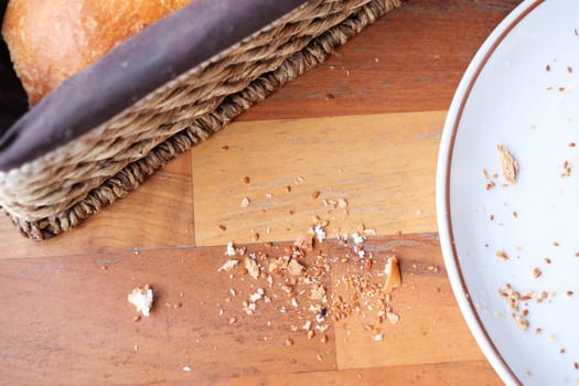 Crumbs are spread across a wooden table next to a woven basket.