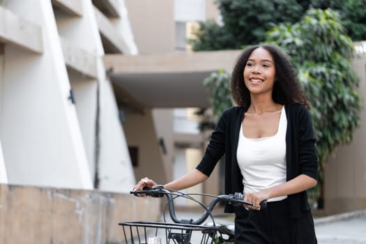 A confident woman rides her bicycle through a modern urban environment, showcasing her commitment to sustainability and healthy living.