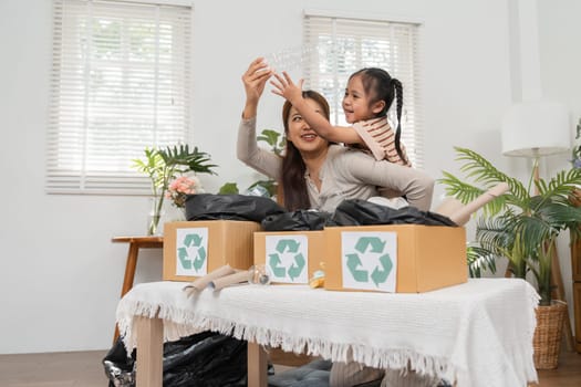 Capturing a playful interaction as the mother encourages her daughter in recycling, reinforcing eco-friendly habits through engaging activities.