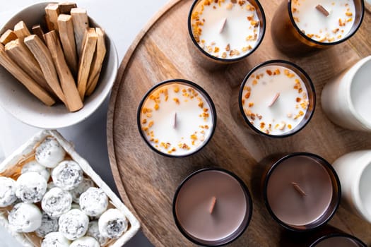 Aromatherapy candles, solid aroma oil in the form of peonies and palo santo displayed on wooden tray.