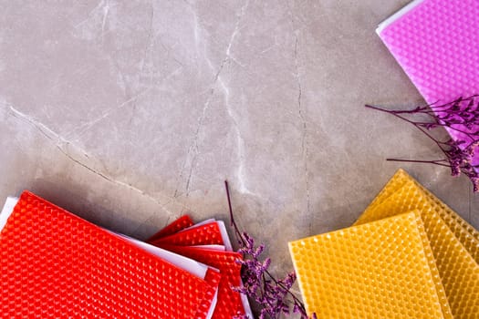 Colorful textured paper sheets with decorative flowers on marble surface.