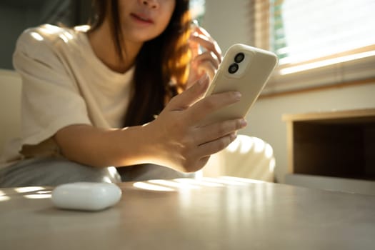Close up shot of smiling woman connecting wireless earbuds to smartphone.
