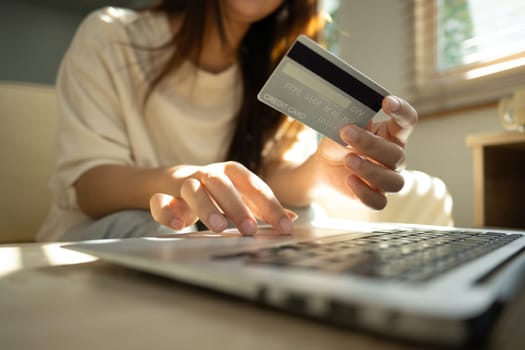 Close up shot of woman making an online payment with credit card and laptop at home.
