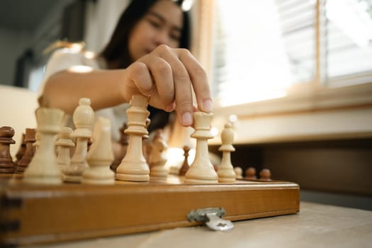 Close up of woman moves a wooden chess piece on a classic chessboard.