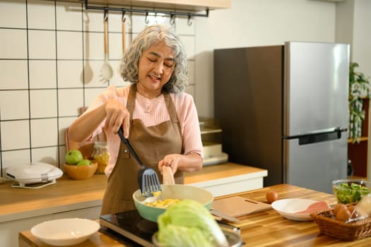 Happy senior woman preparing a healthy meal in a warm kitchen.