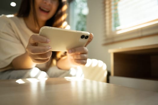 Excited woman playing a game on her smartphone in bright living room.