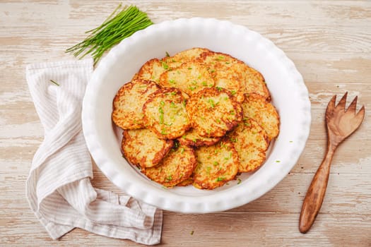 Crispy potato pancakes in large serving bowl with chives