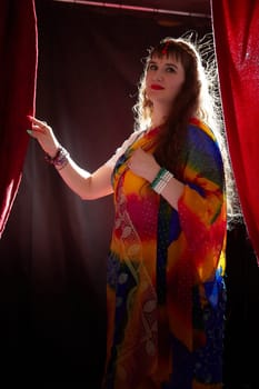 A mature woman in a colorful sari poses elegantly, showcasing her style and confidence during a creative Indian-themed shoot.