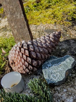 A heartfelt memorial display near the Eglise Saint Pierre in Mons, Gironde showcases natural elements like pinecones and stones inscribed with love, reflecting peace and remembrance.